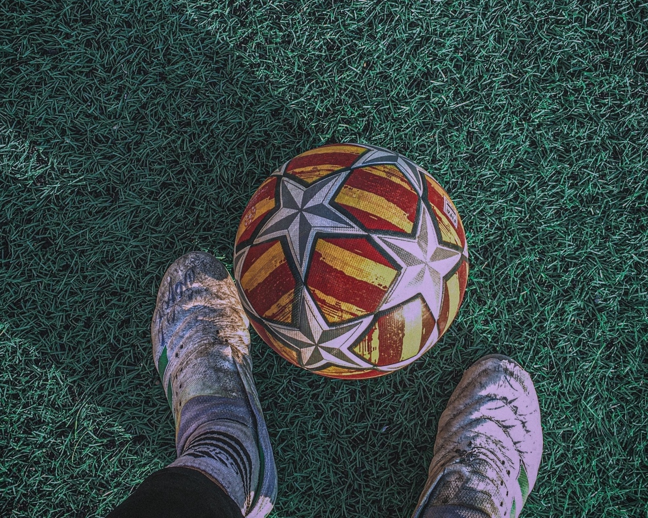 Футбольный мяч на зеленом поле с ногами футболиста