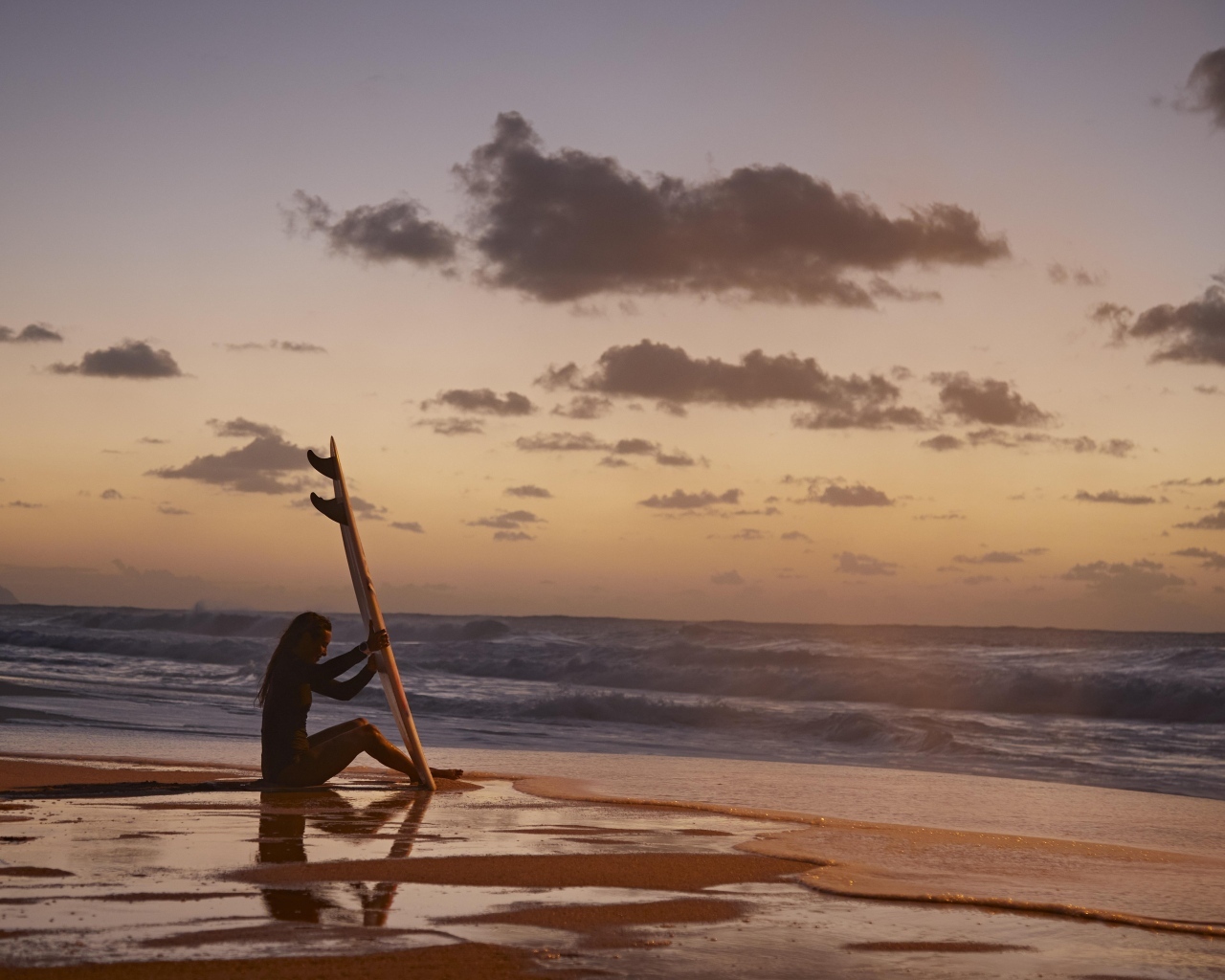 Surfer girl sitting on the seashore