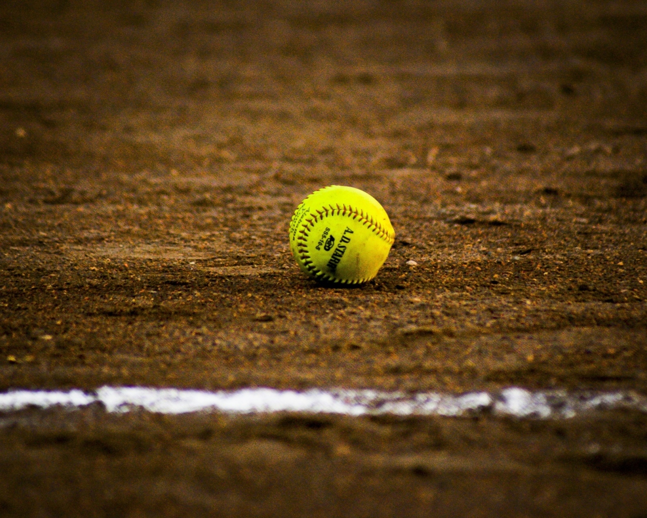 Желтый бейсбольный мяч на песке