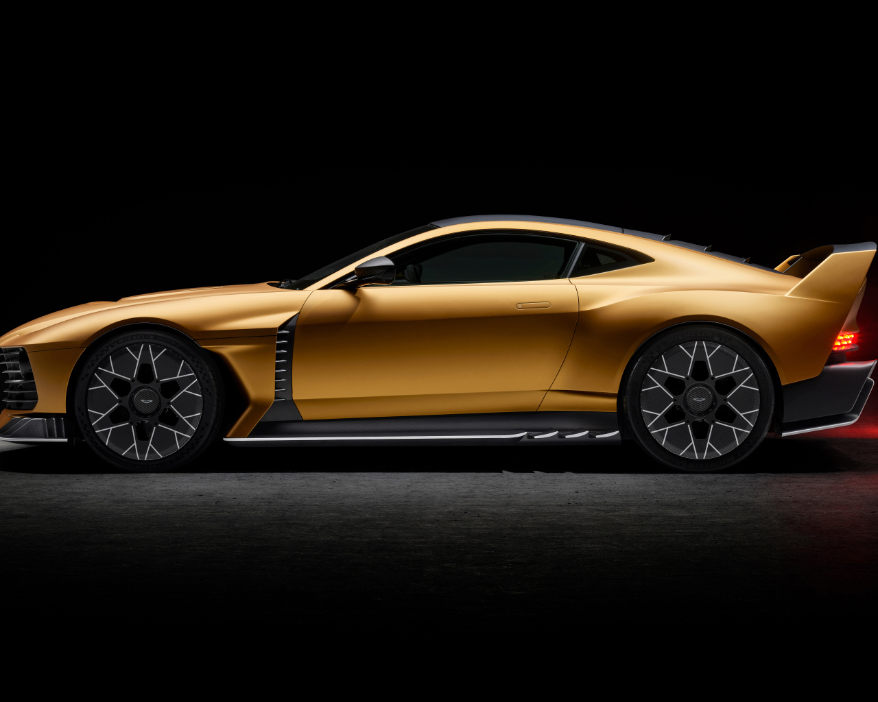 Вид сбоку на золотистый спортивный автомобиль Aston Martin Valiant 2024 года