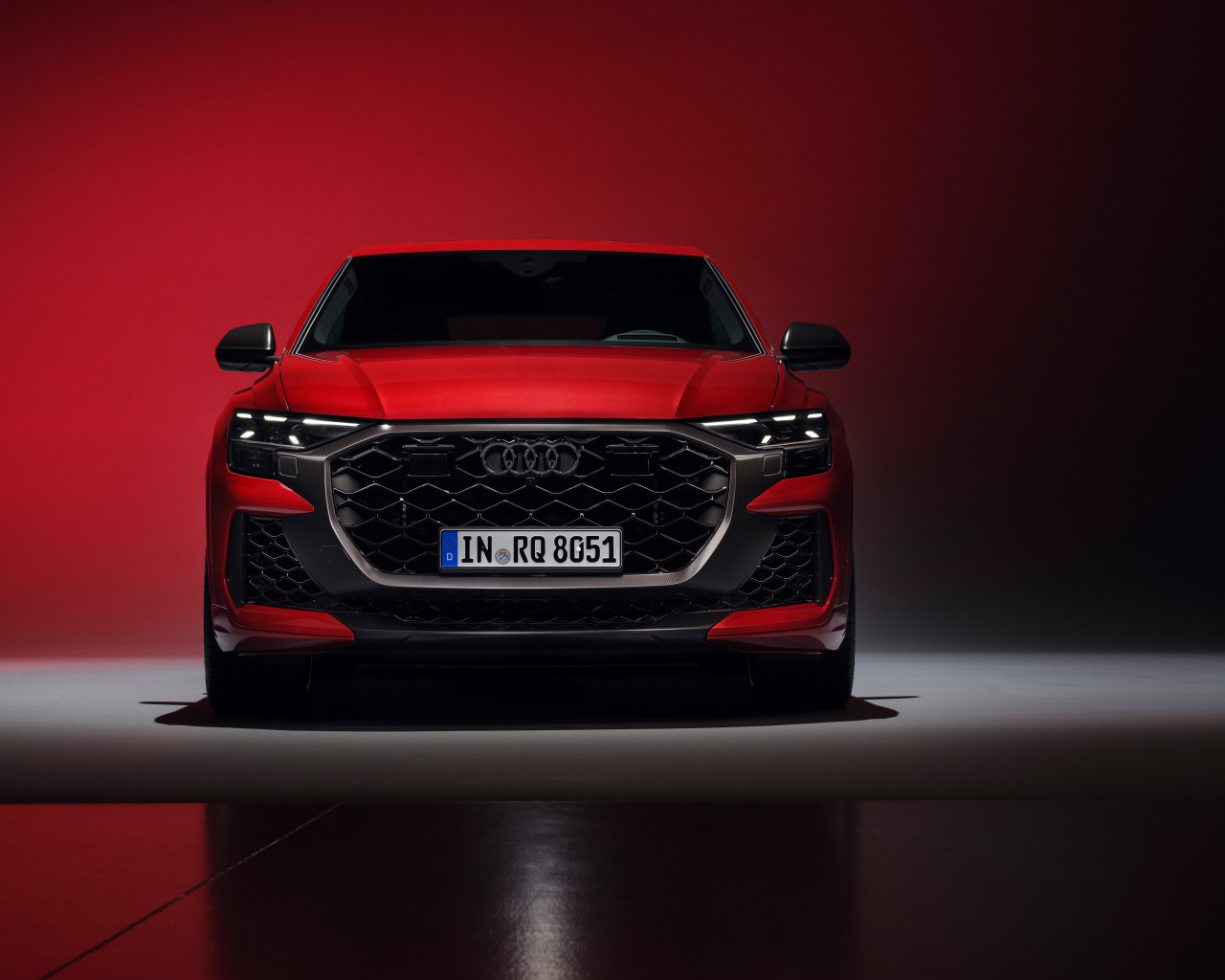 Вид спереди на автомобиль Audi RS Q8 performance 2024 года на красном фоне