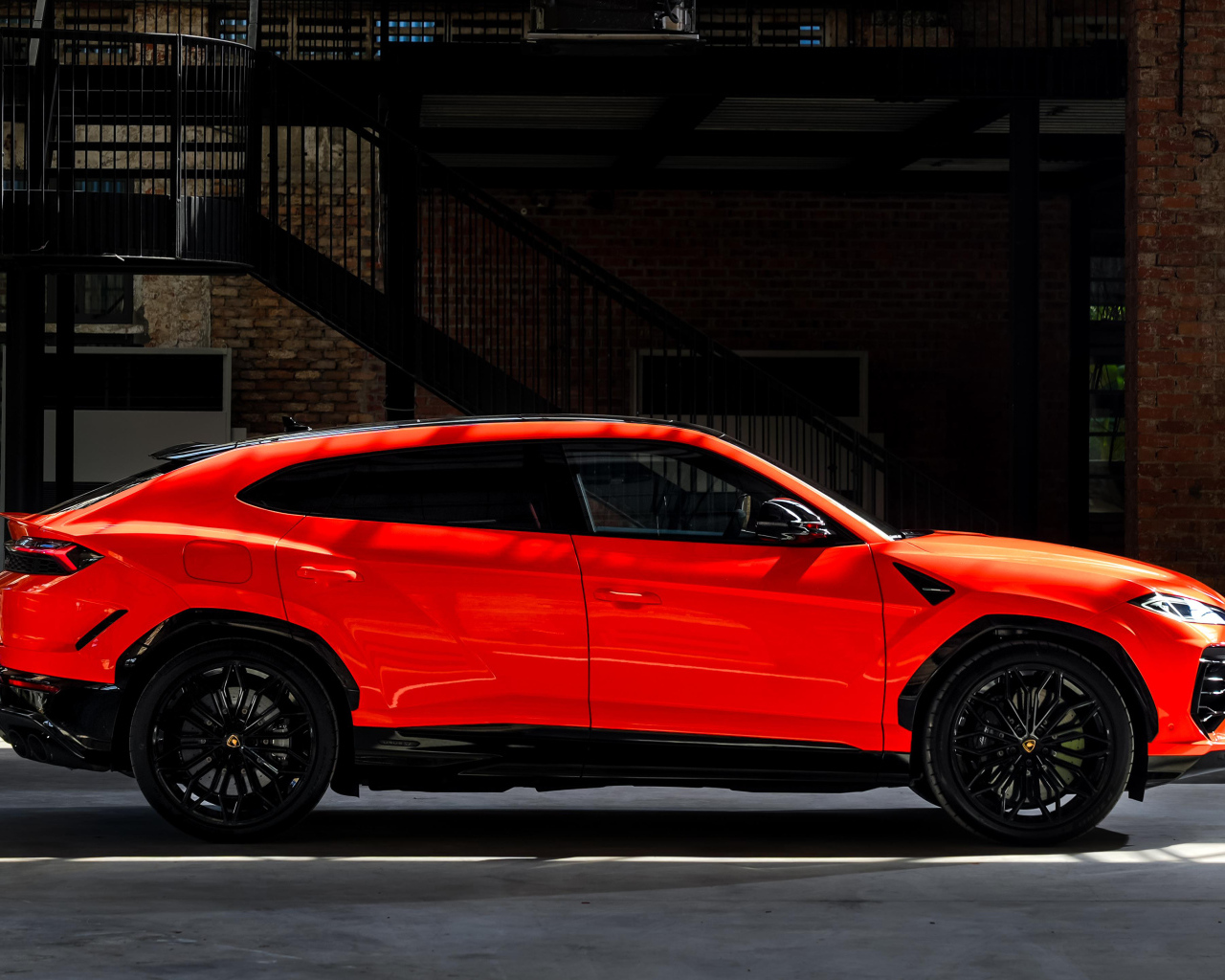 Вид сбоку на красный внедорожник Lamborghini Urus