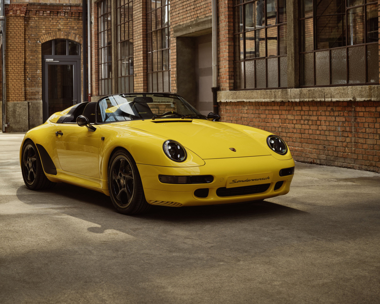 Желтый автомобиль Porsche 911 Speedster Sonderwunsch 2024 года у здания