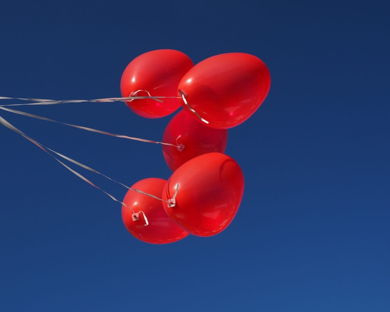 Красные воздушные шары на нитке на фоне голубого неба