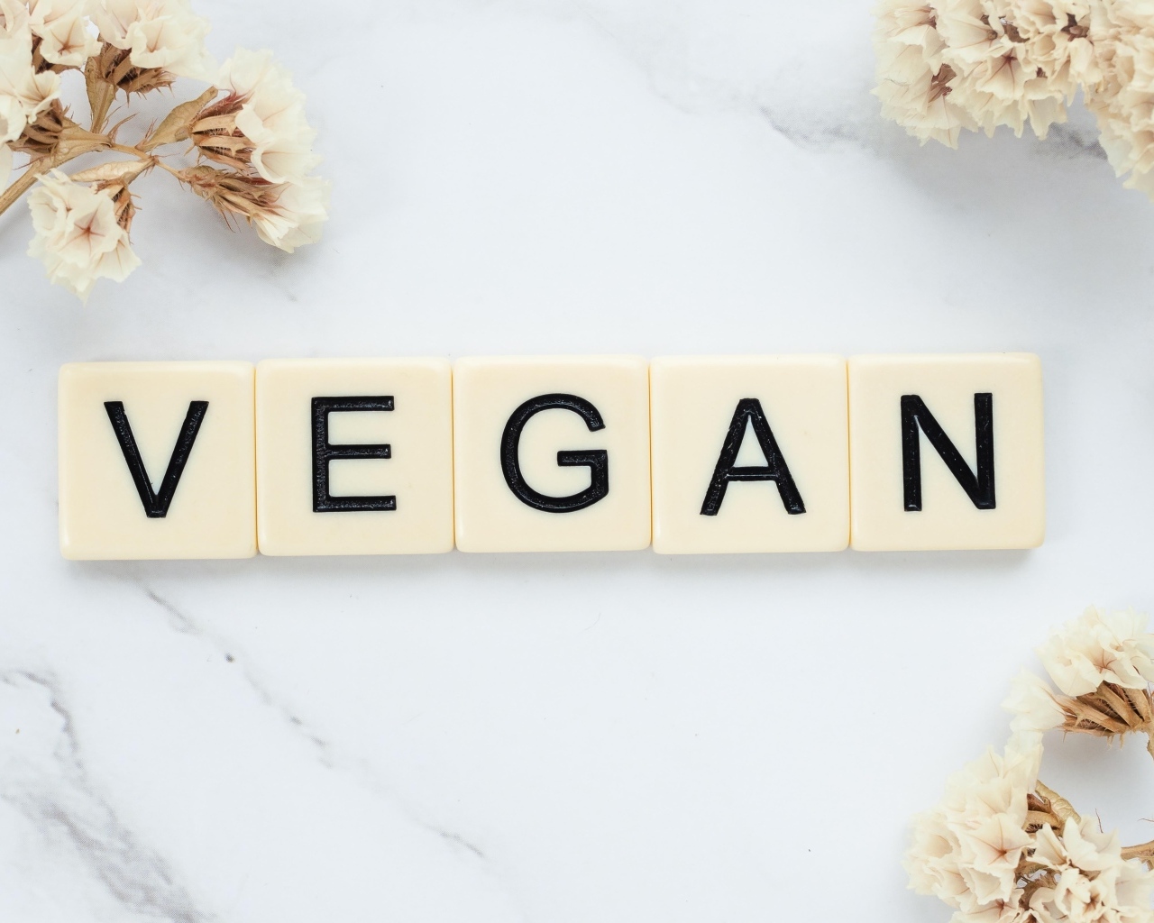 Надпись веган на столе с цветами