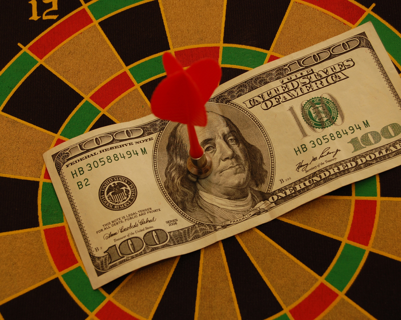 Купюра сто долларов на доске для дартс