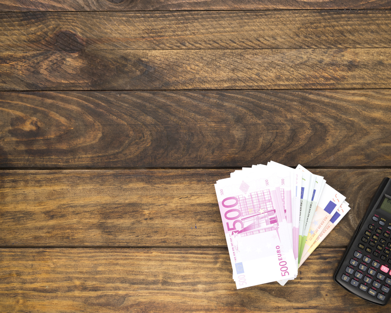 Купюры и калькулятор на деревянном фоне