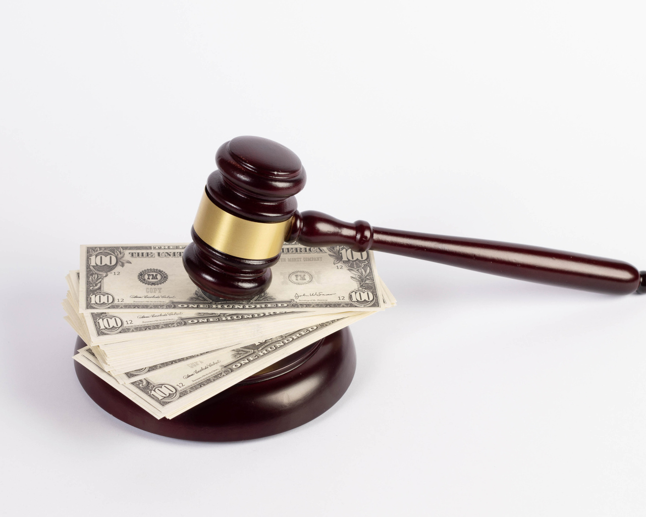 Молоток судьи и пачка долларов на белом фоне