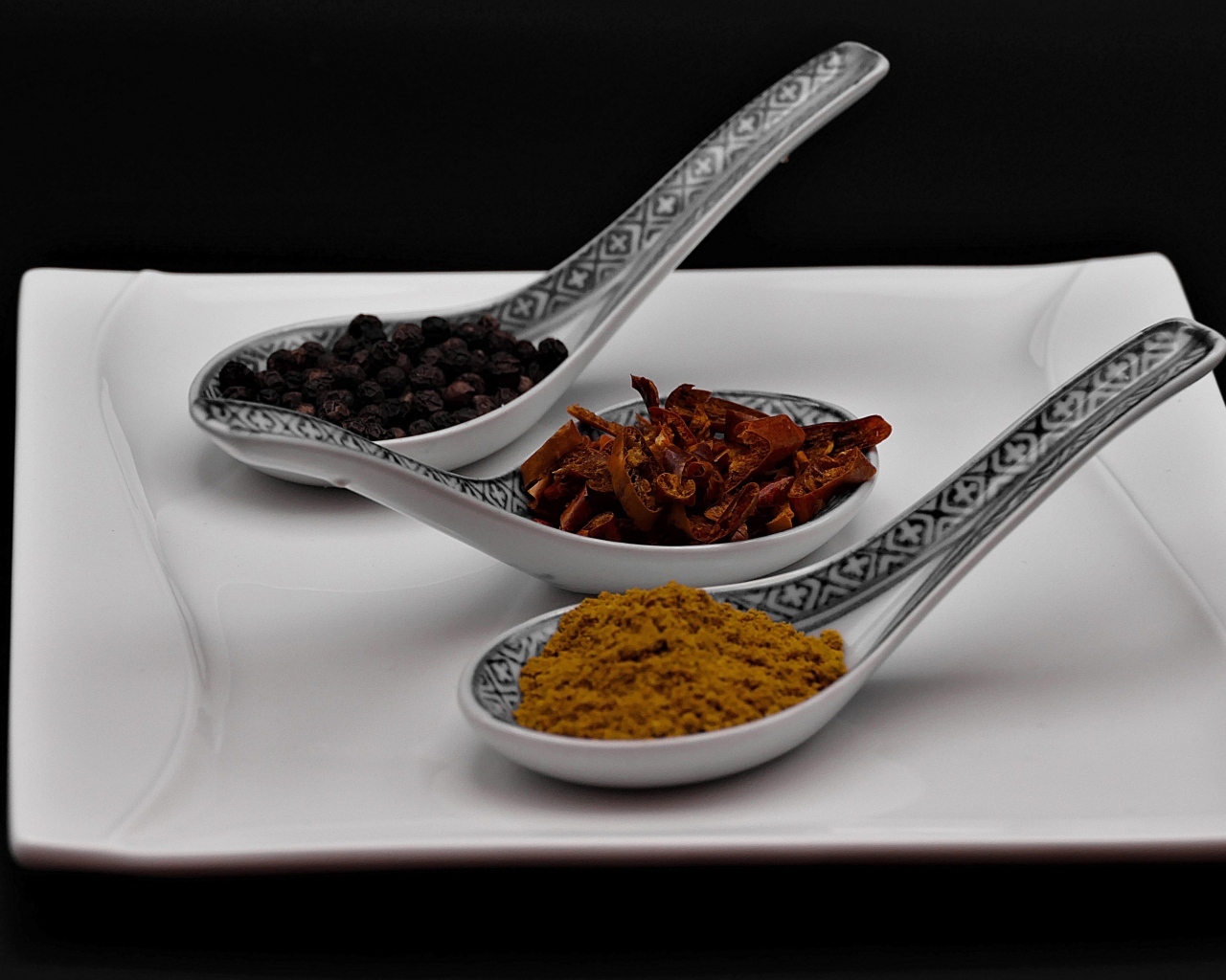 Ароматные специи в ложках на белой тарелке