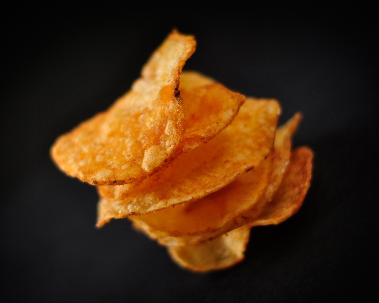 Хрустящие картофельные чипсы на черном фоне