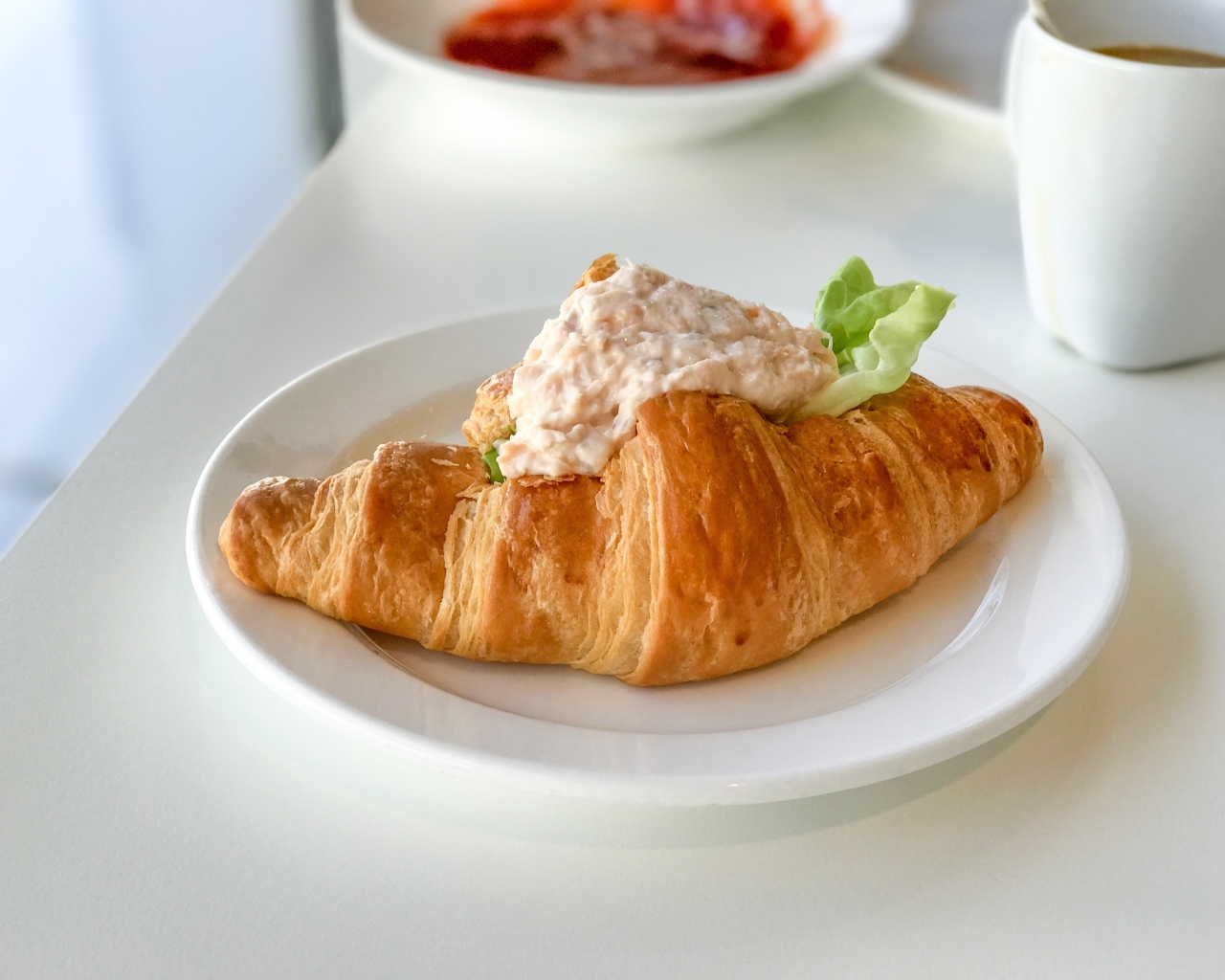 Круассан с начинкой на белой тарелке на завтрак 