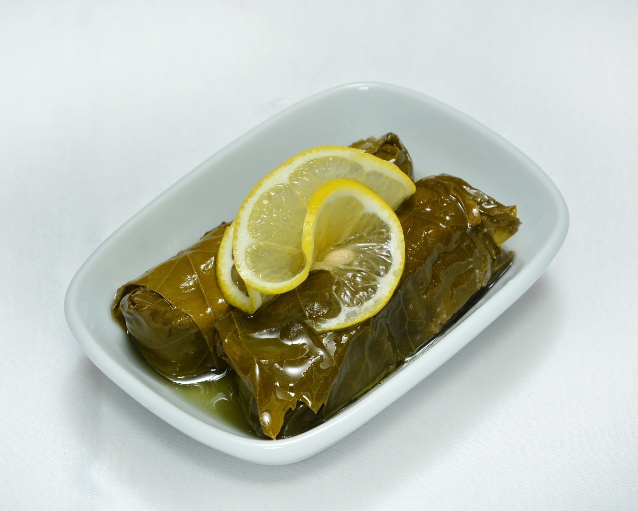 Долма с лимоном с тарелке на сером фоне