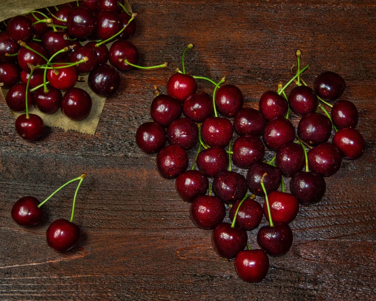 Сердце из спелых ягод черешни на деревянном столе