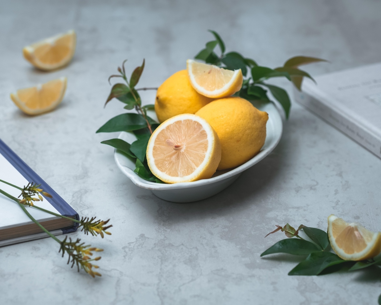 Лимон с зелеными листьями на столе с книгами