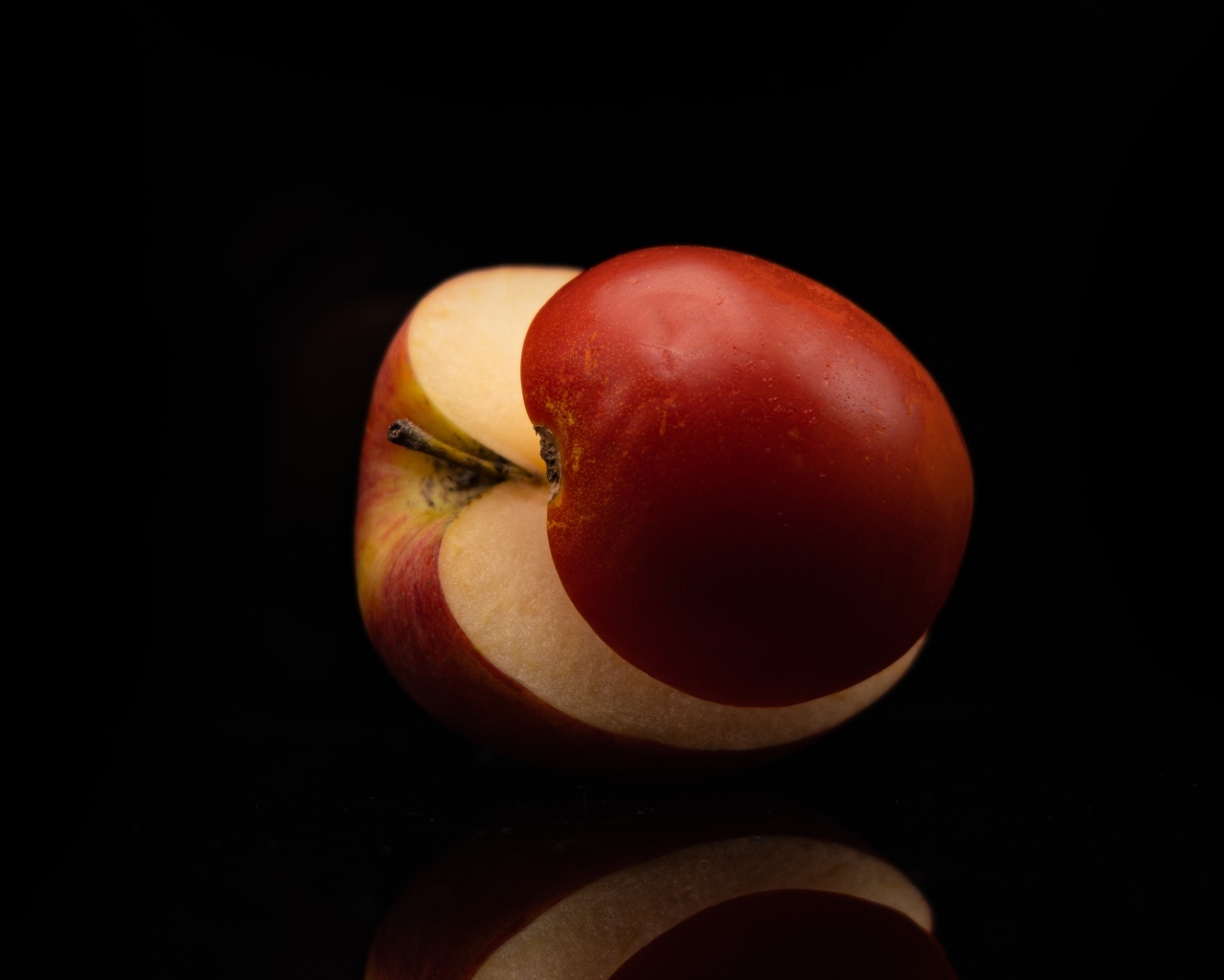Разрезанное на половинки красное яблоко на черном фоне