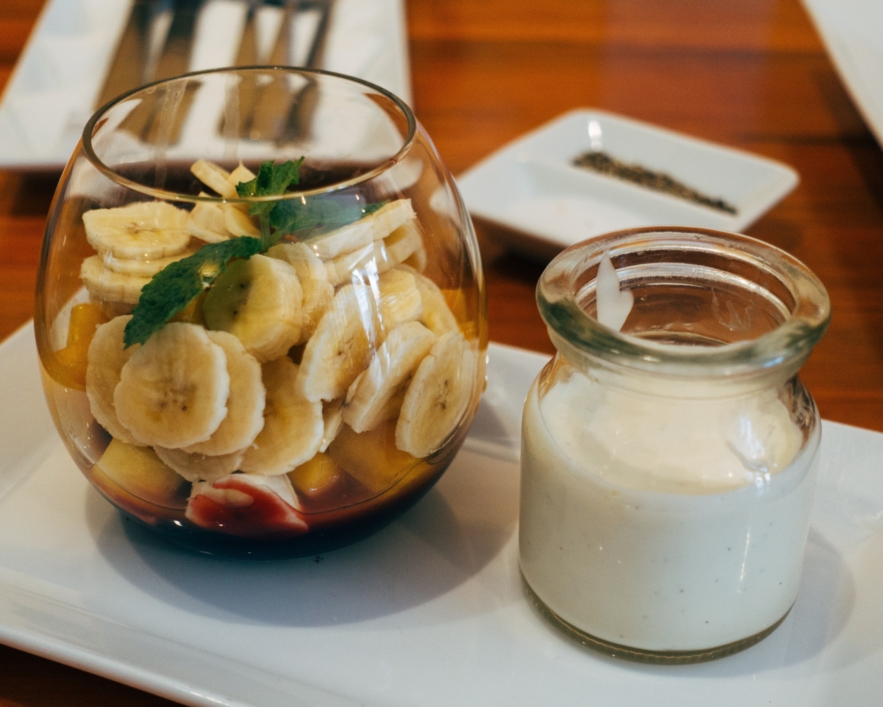 Нарезанные бананы в стакане на столе с йогуртом