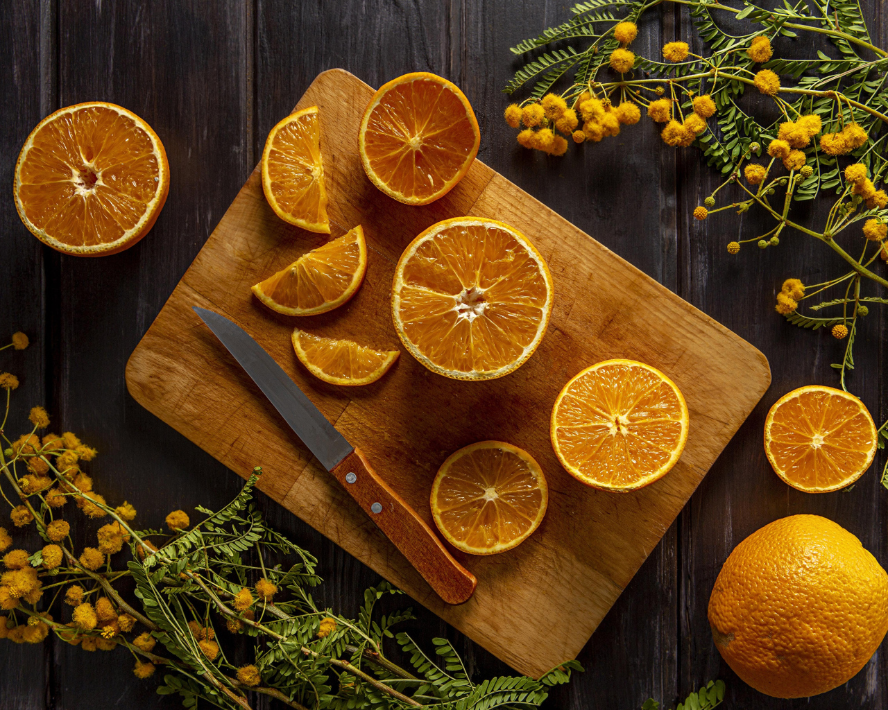 Нарезанный апельсин на доске на столе с цветами