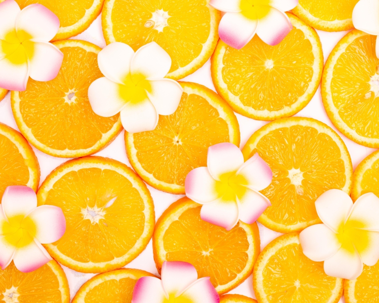 Нарезанный апельсин с цветами плюмерии для фона