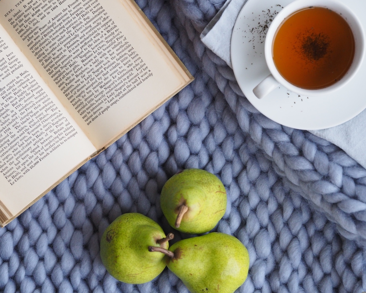 Три зеленые груши на столе с чаем и книгой