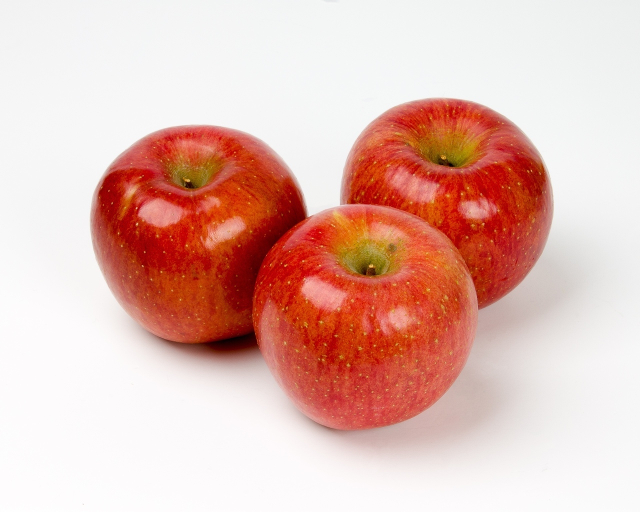 Три красных яблока на белом фоне
