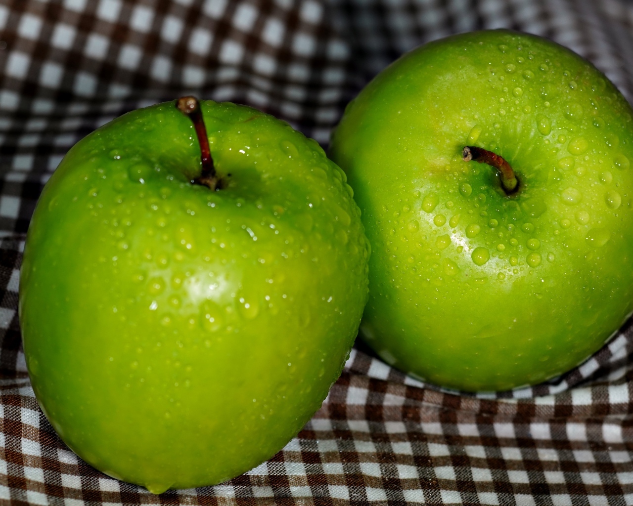 Два мокрых зеленых яблока на скатерти