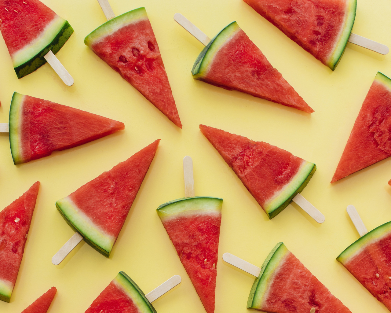 Куски арбуза на палочке на желтом фоне
