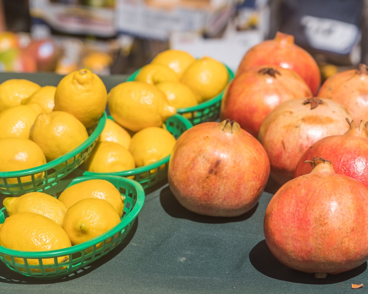 Желтые лимоны и красные плоды граната на столе