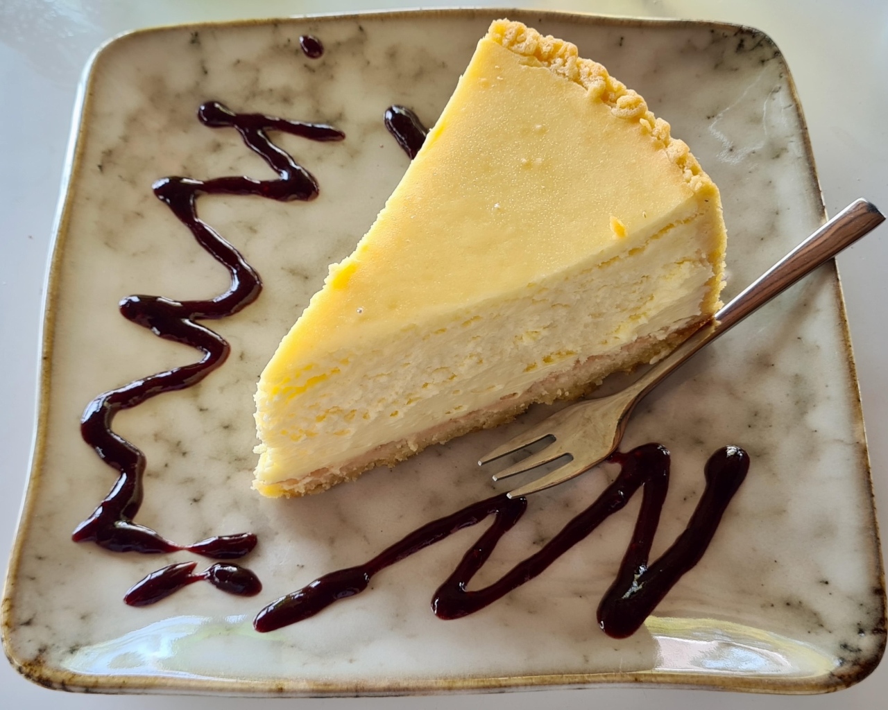 Кусок чизкейка с шоколадным топпингом на тарелке