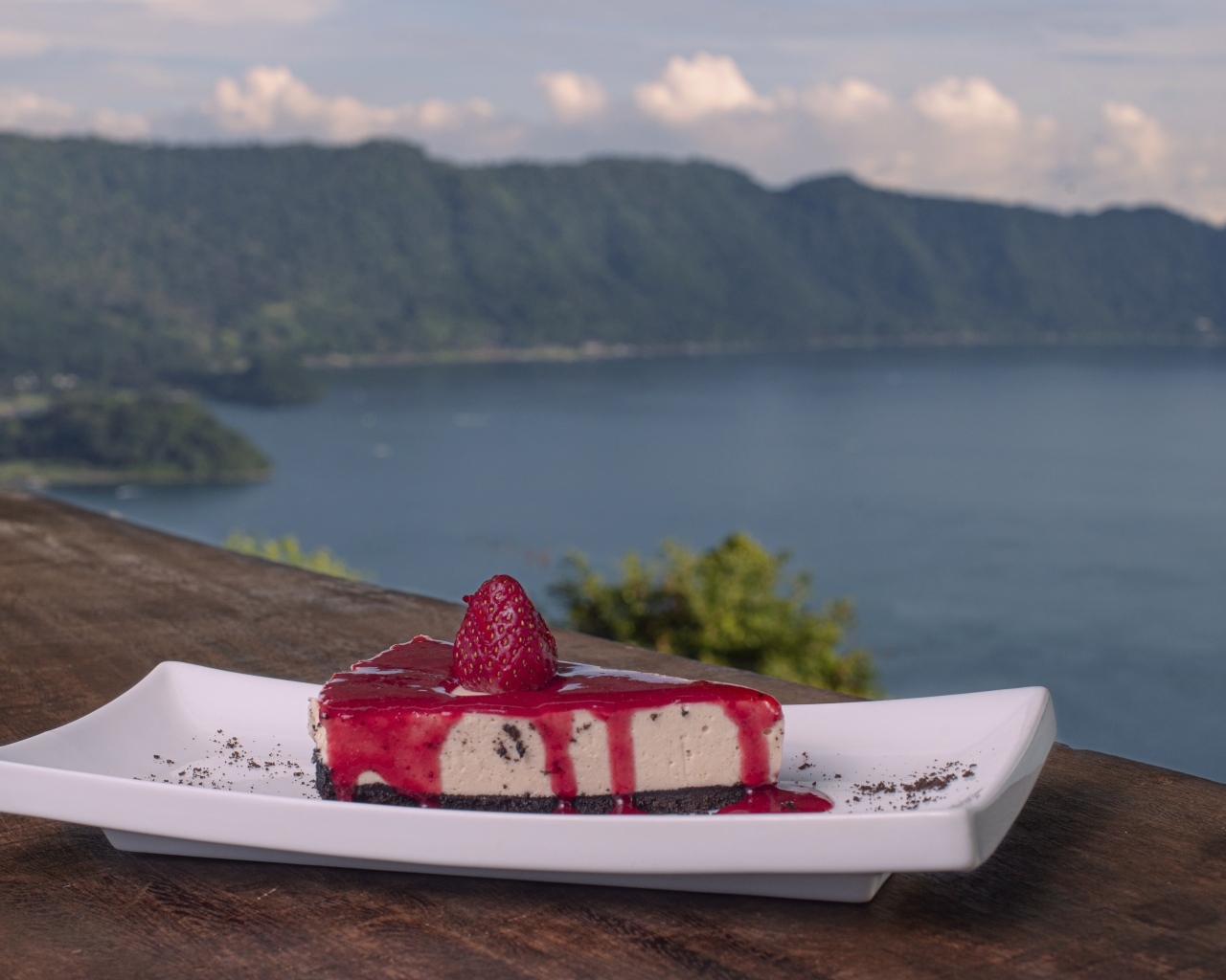 Кусок чизкейка с клубничным джемом на фоне моря