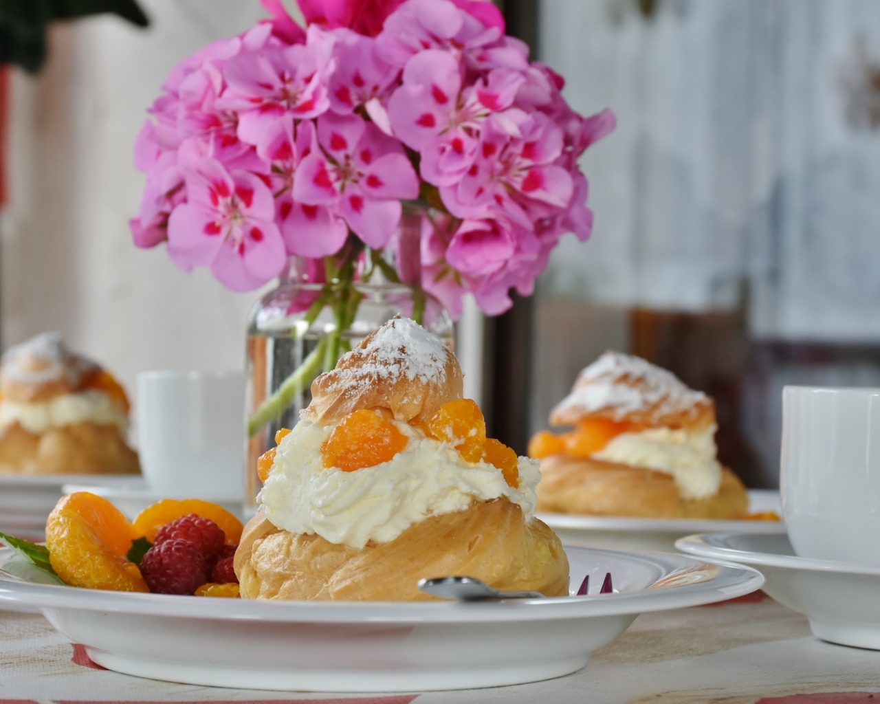 Булочки с кремом и фруктами на столе с букетом