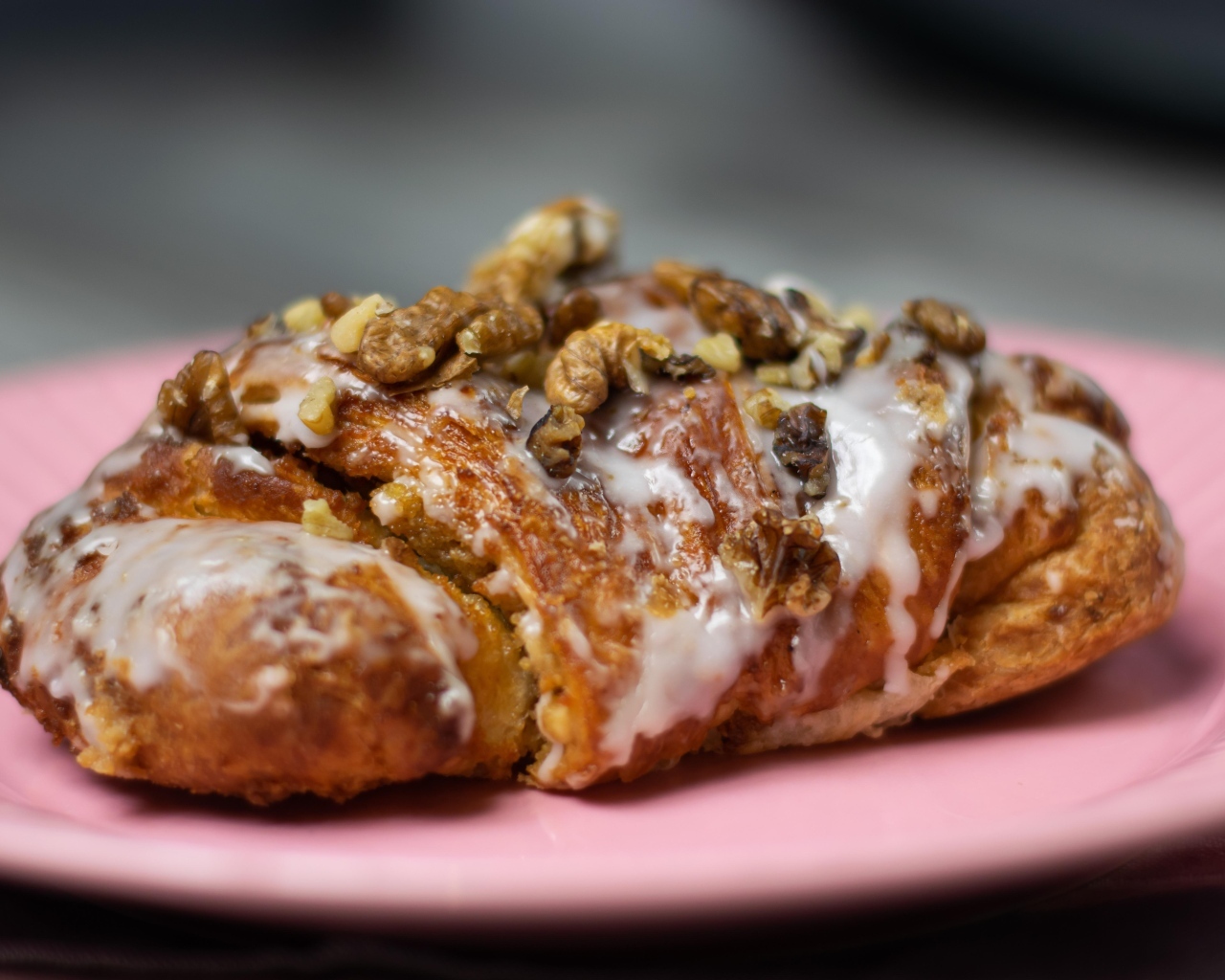 Круассан с кремом и грецкими орехами на розовой тарелке