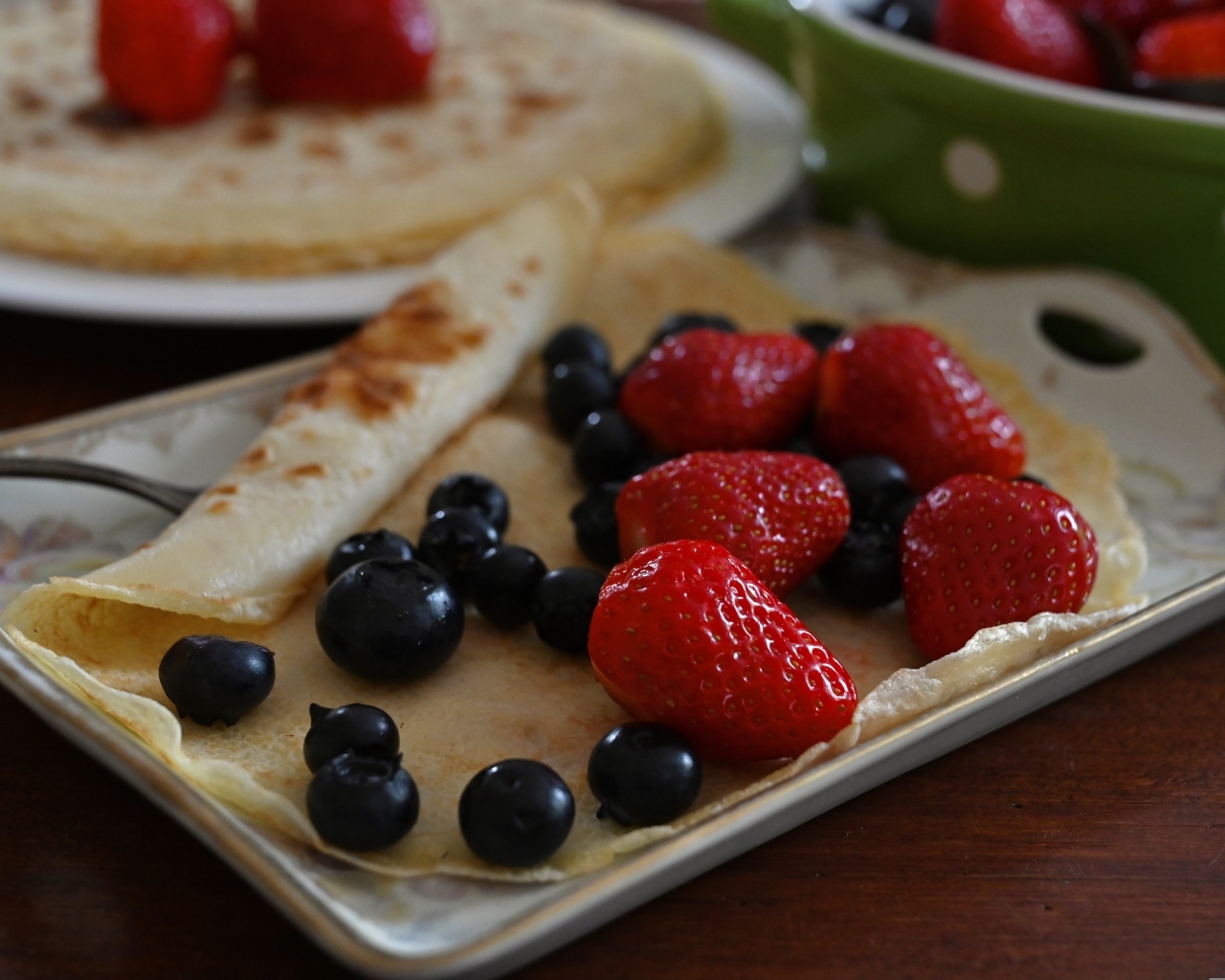 Блин с ягодами черники и клубники на тарелке