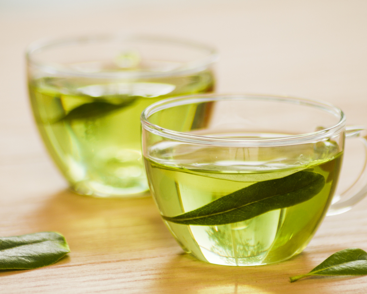 Две чашки зеленого чая с листьями