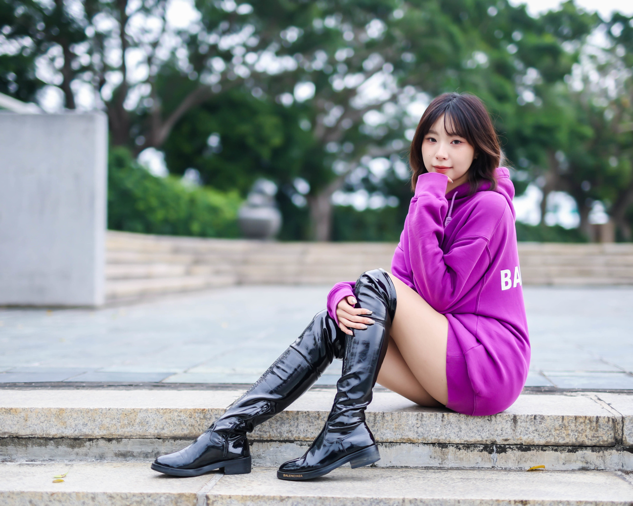 Asian girl in long black boots sitting on the steps
