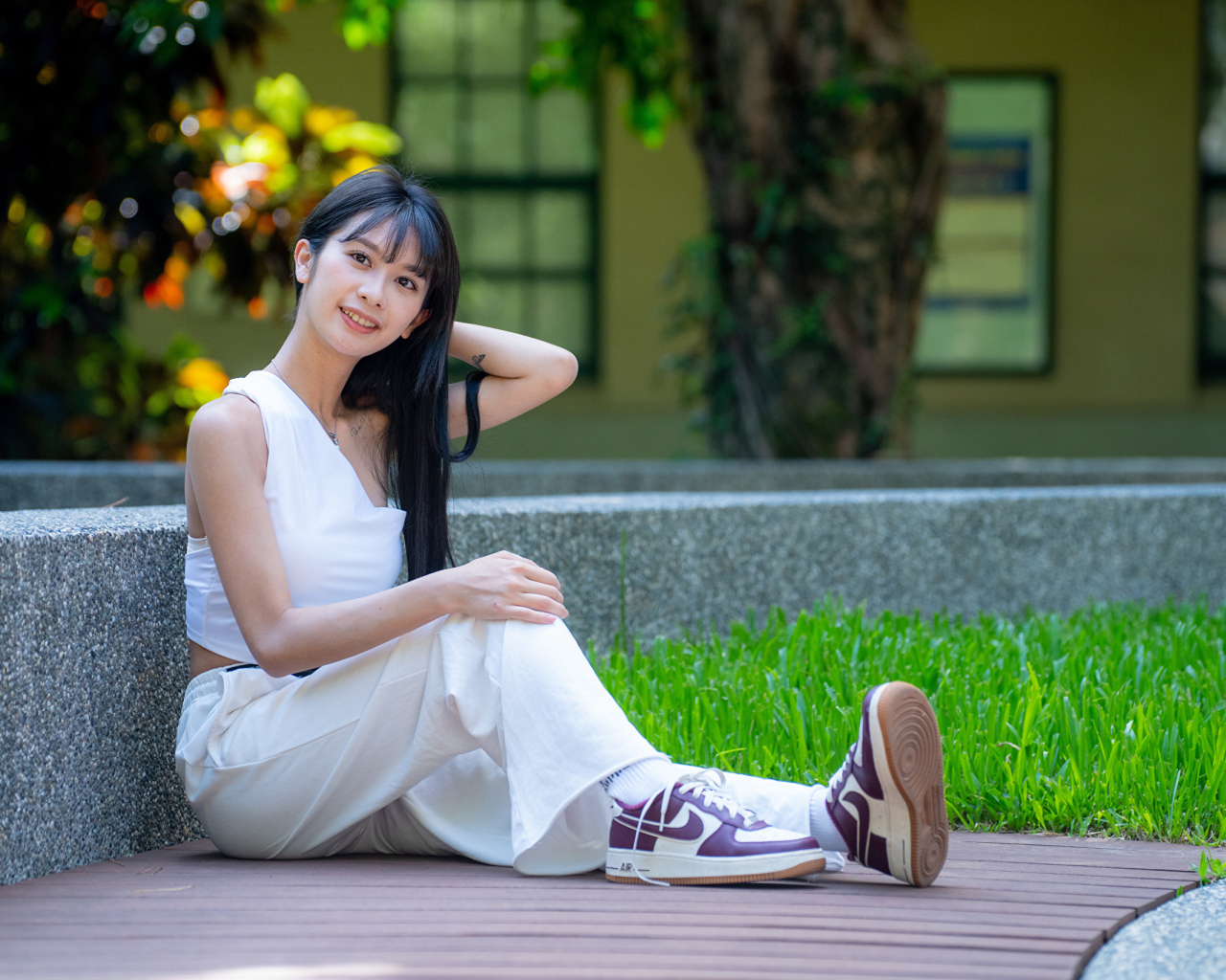 Девушка азиатка в белой костюме сидит на земле