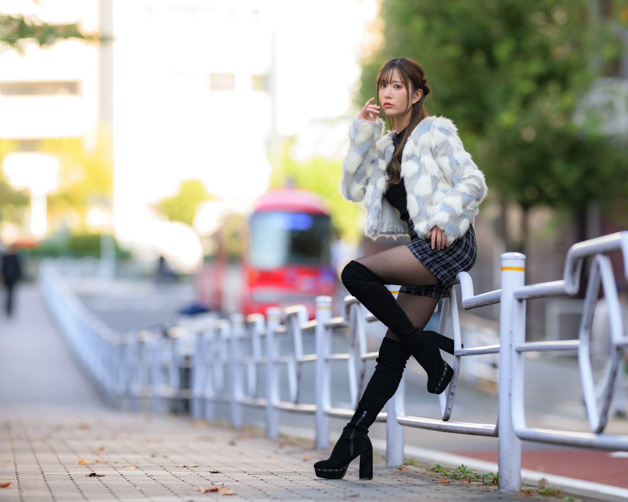 Азиатка в шубе стоит у забора