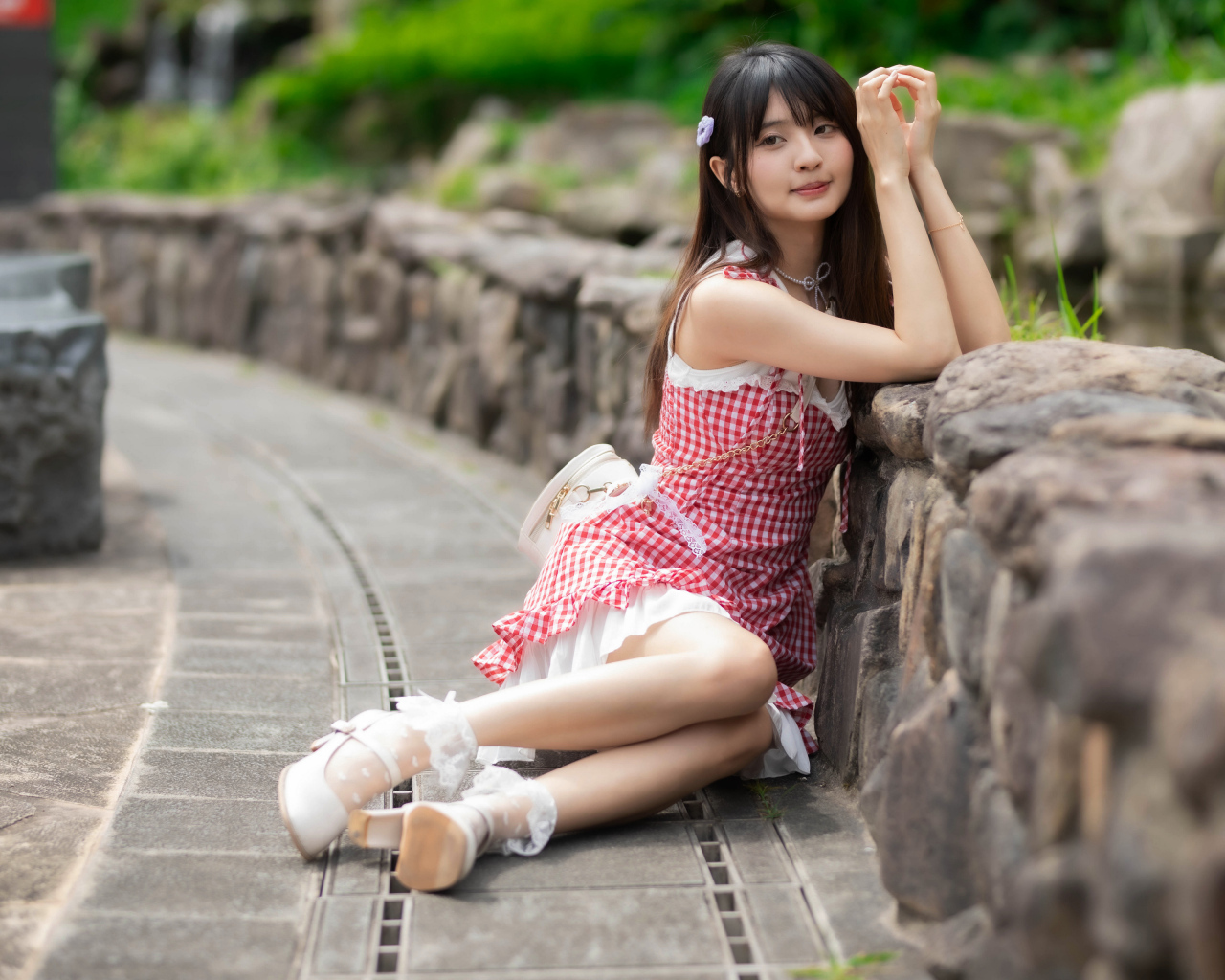 Азиатка сидит на земле в красном платье