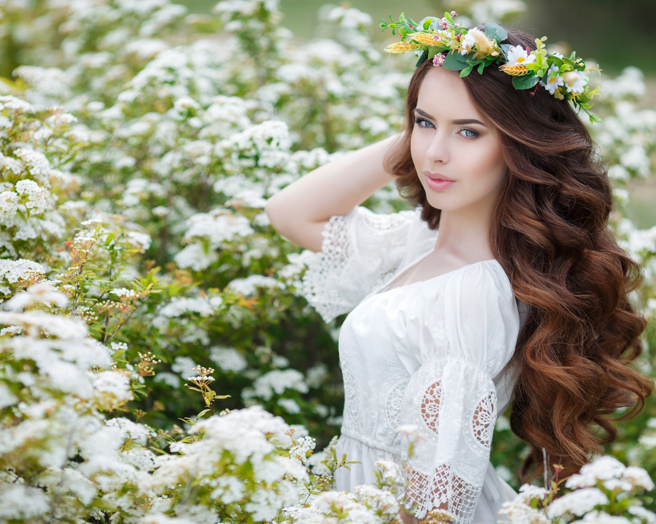 Красивая девушка в белом платье с венком на голове в белых цветах
