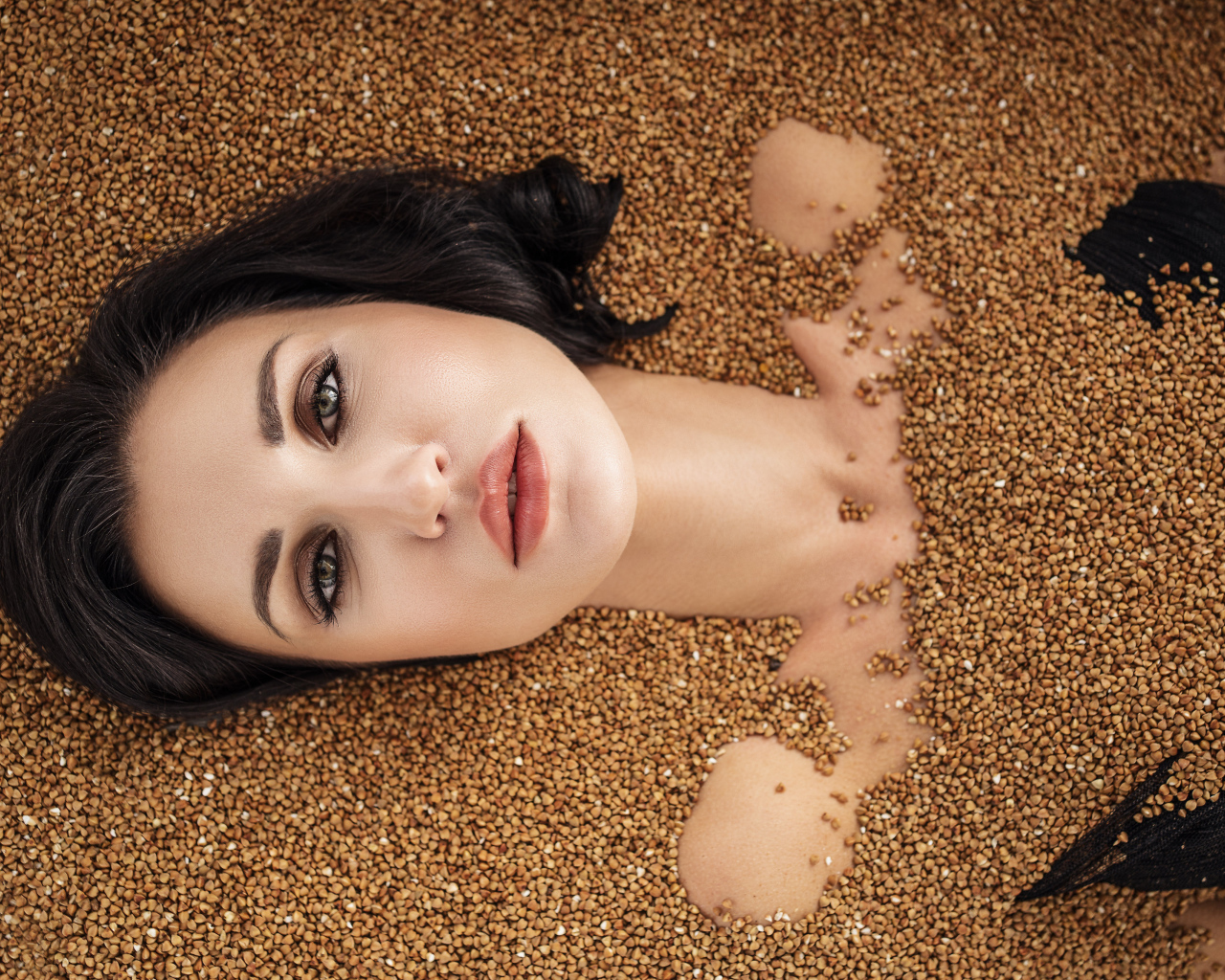 Красивая девушка лежит в зернах гречки