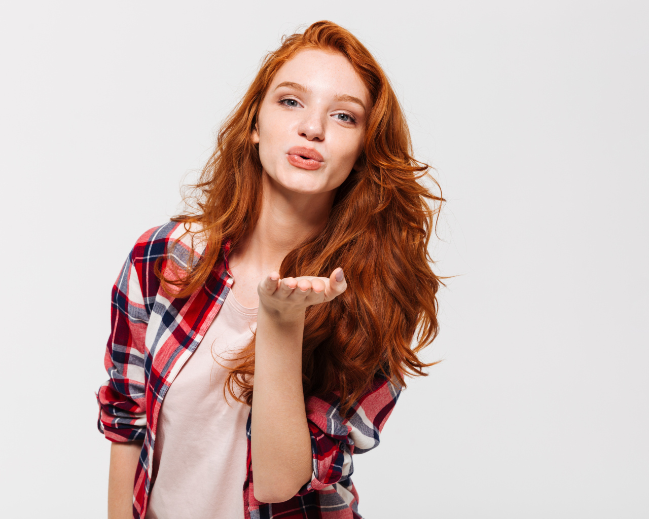 Красивая рыжеволосая девушка шлет воздушный поцелуй