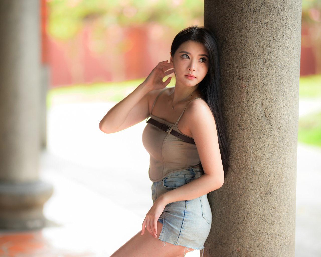 Милая длинноволосая азиатка стоит у колонны