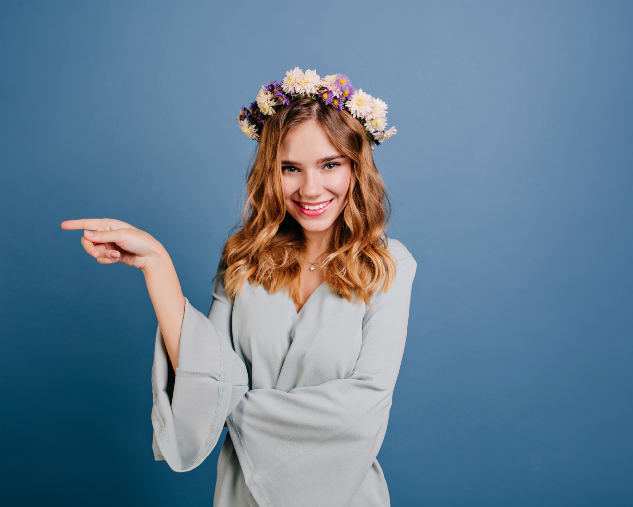 Милая улыбающаяся девушка с венком на голове на сером фоне