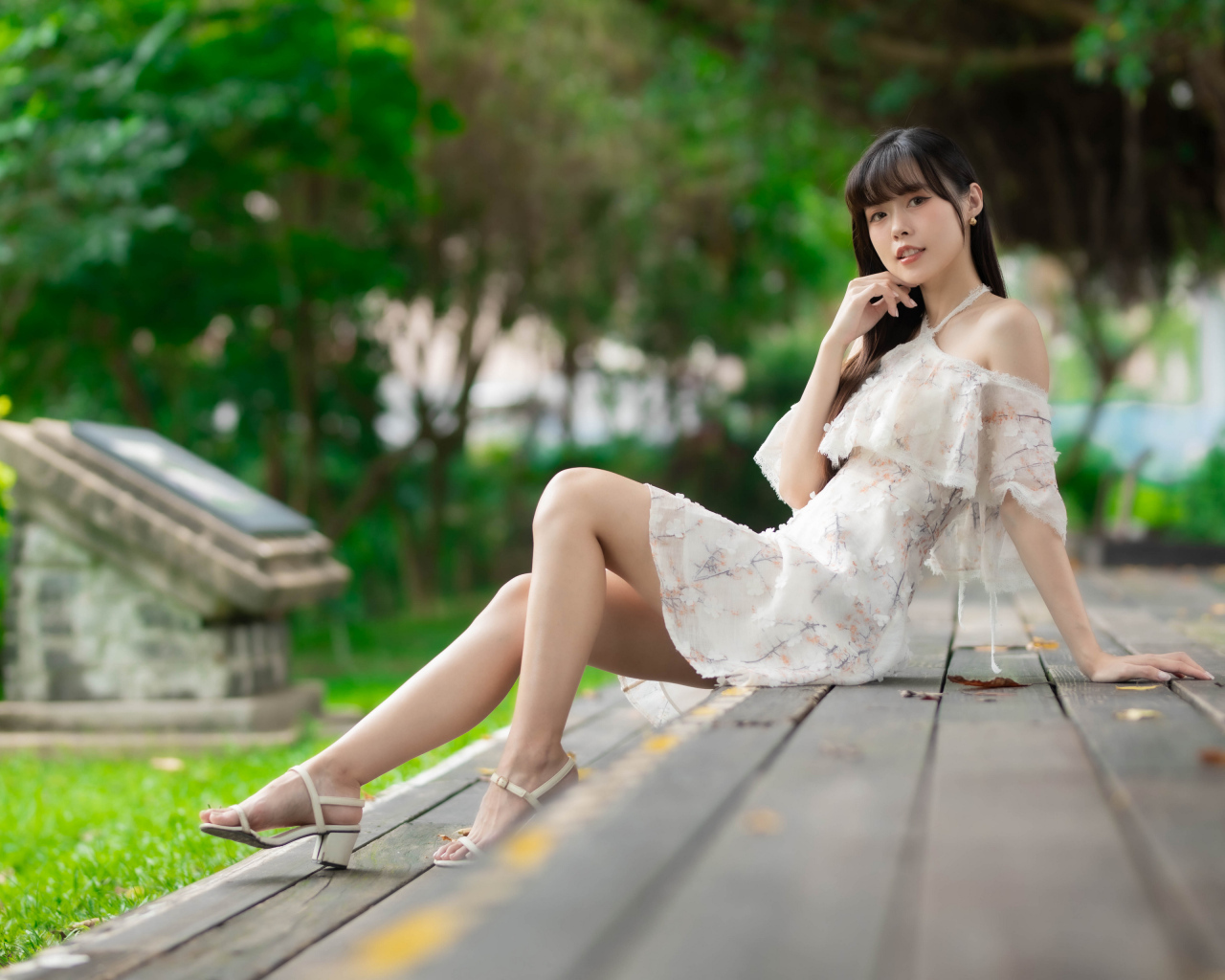 Симпатичная молодая азиатка сидит на деревянном покрытии