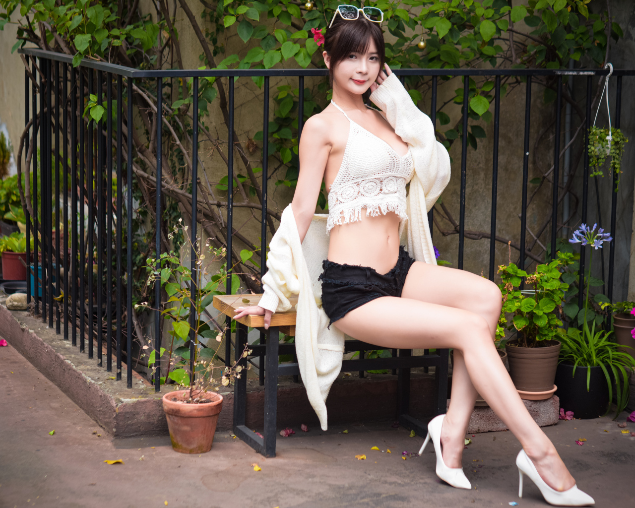 Стройная девушка азиатка сидит на лавке у дома