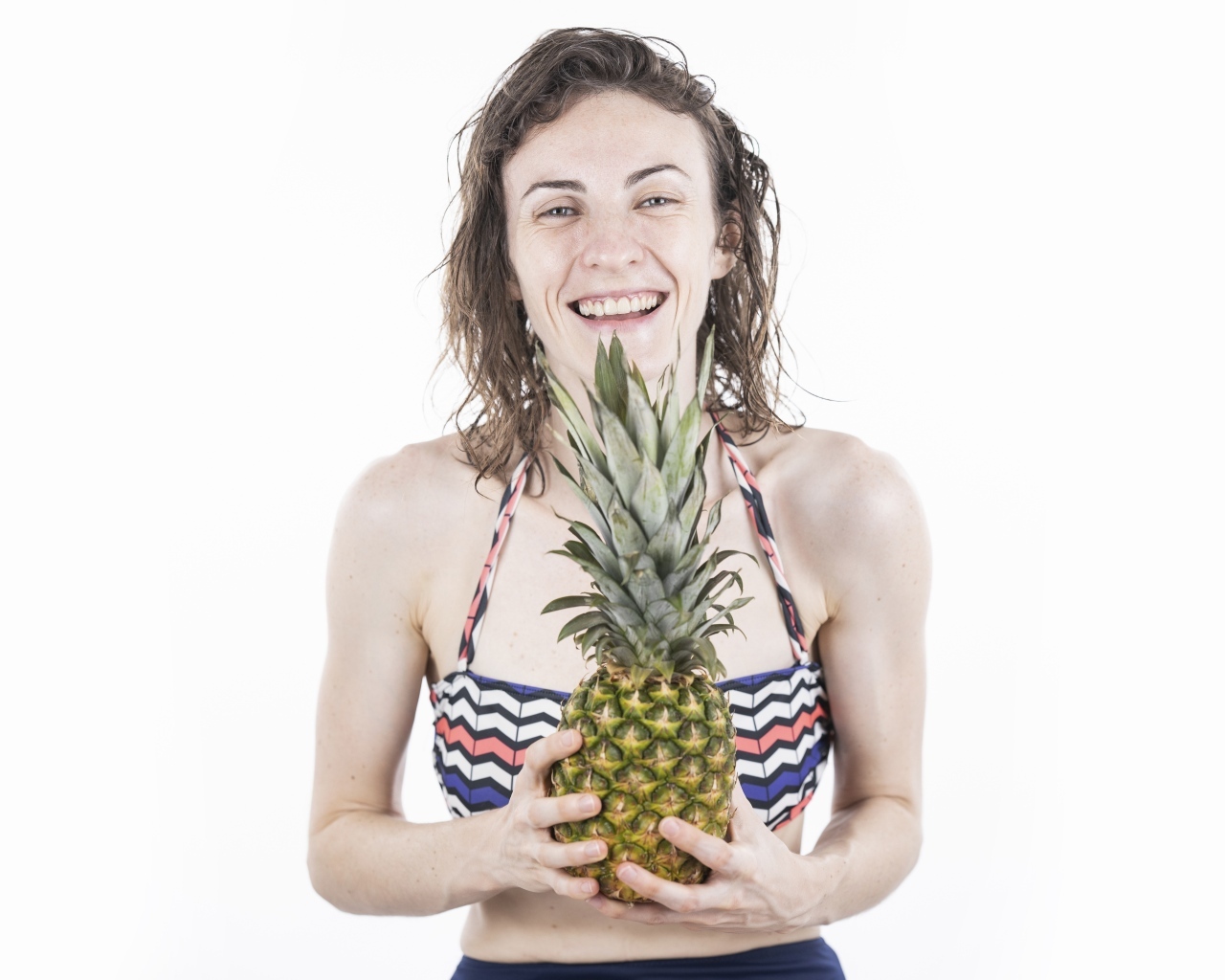 Улыбающаяся девушка с ананасом в руках