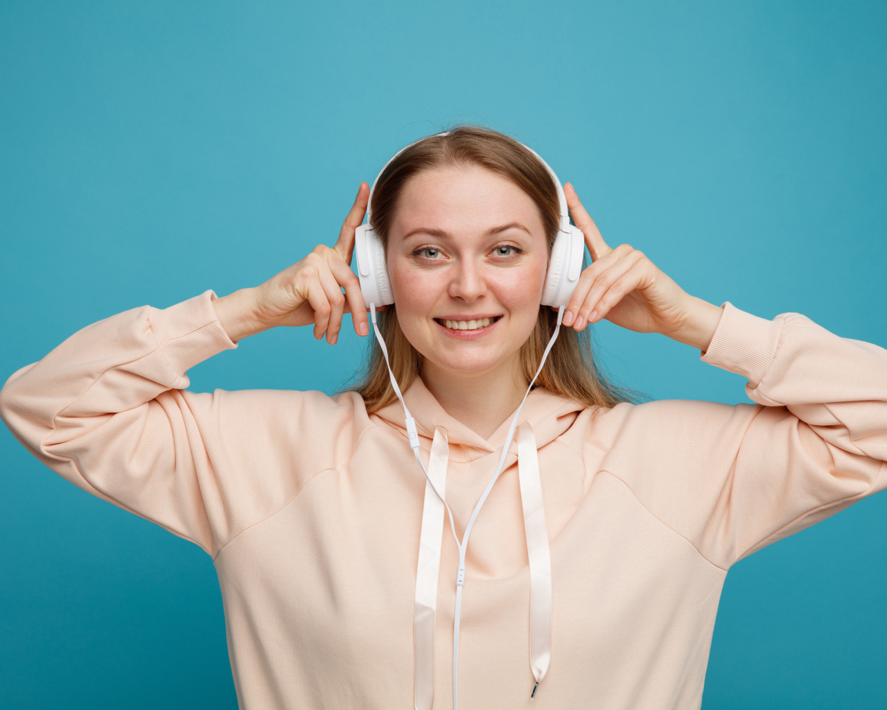 Улыбающаяся девушка в наушниках на голубом фоне