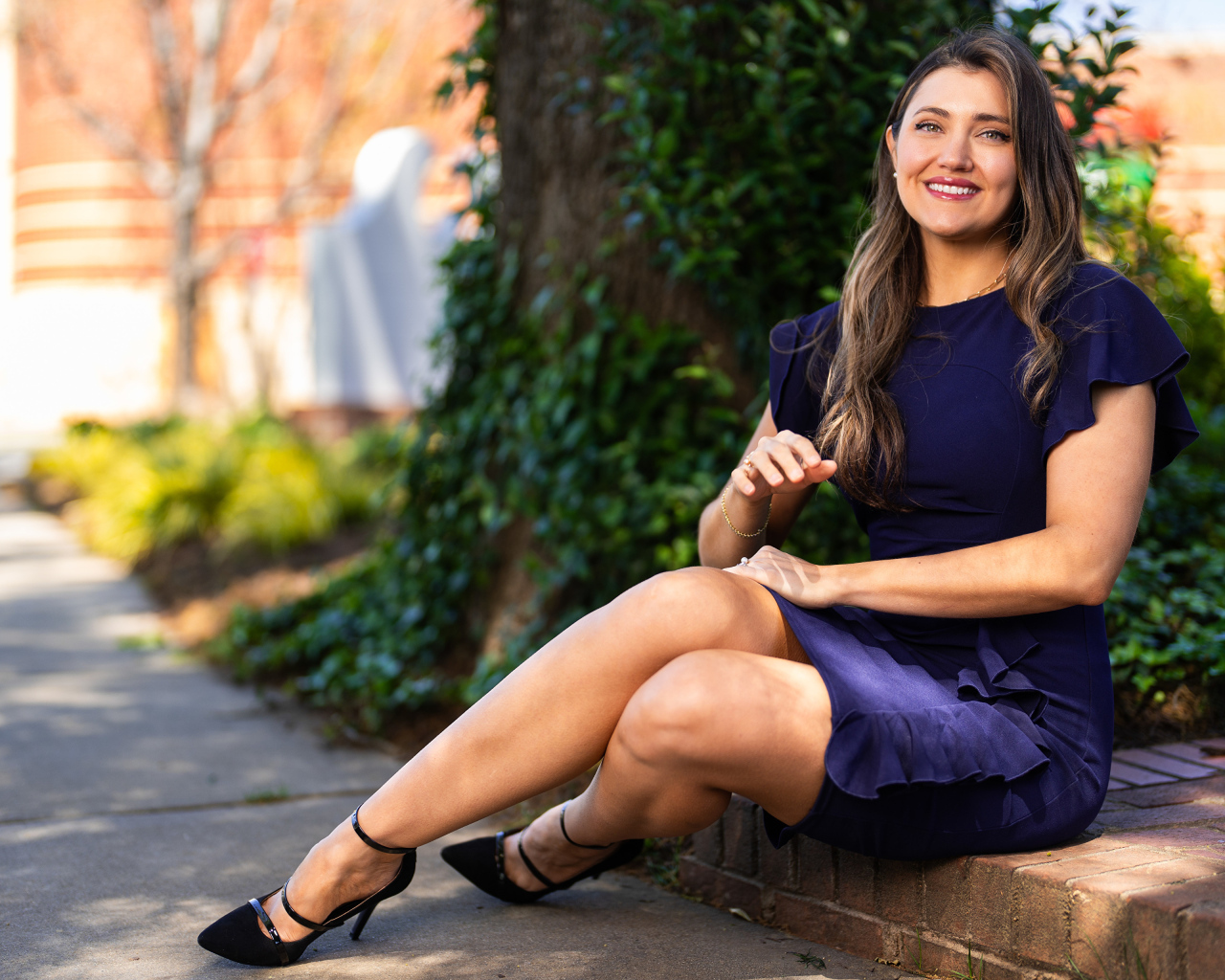 Улыбающаяся женщина в синем платье сидит на земле