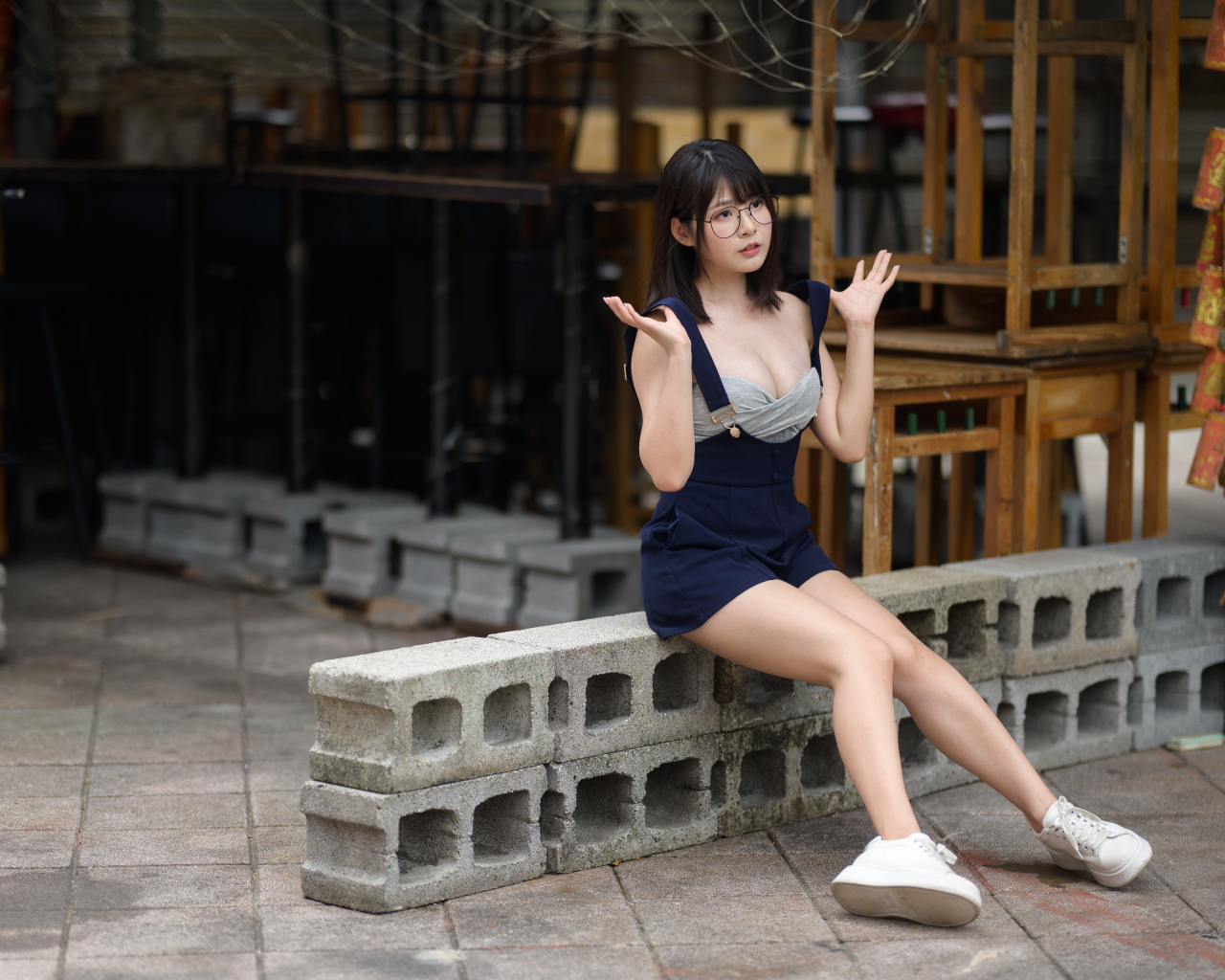 Молодая азиатка в очках сидит на шлакоблоке