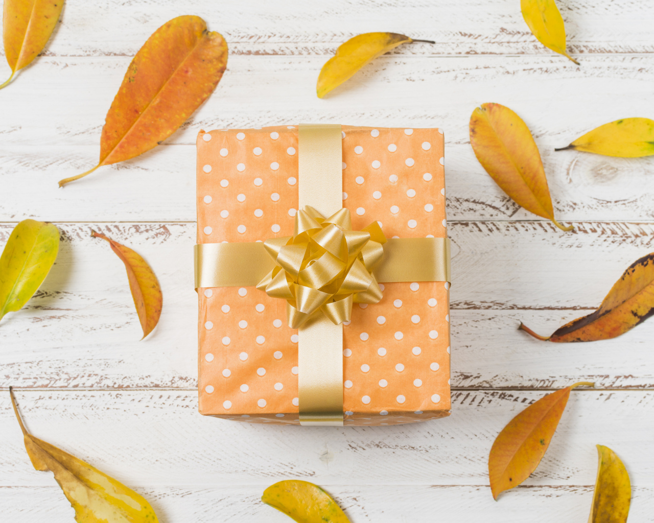 Подарок с желтыми листьями на белом фоне