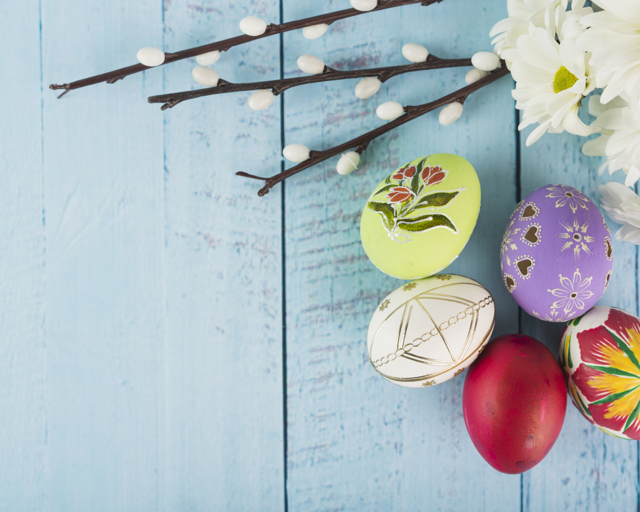 Красивые пасхальные яйца с ветками вербы и цветами хризантемы на голубом фоне